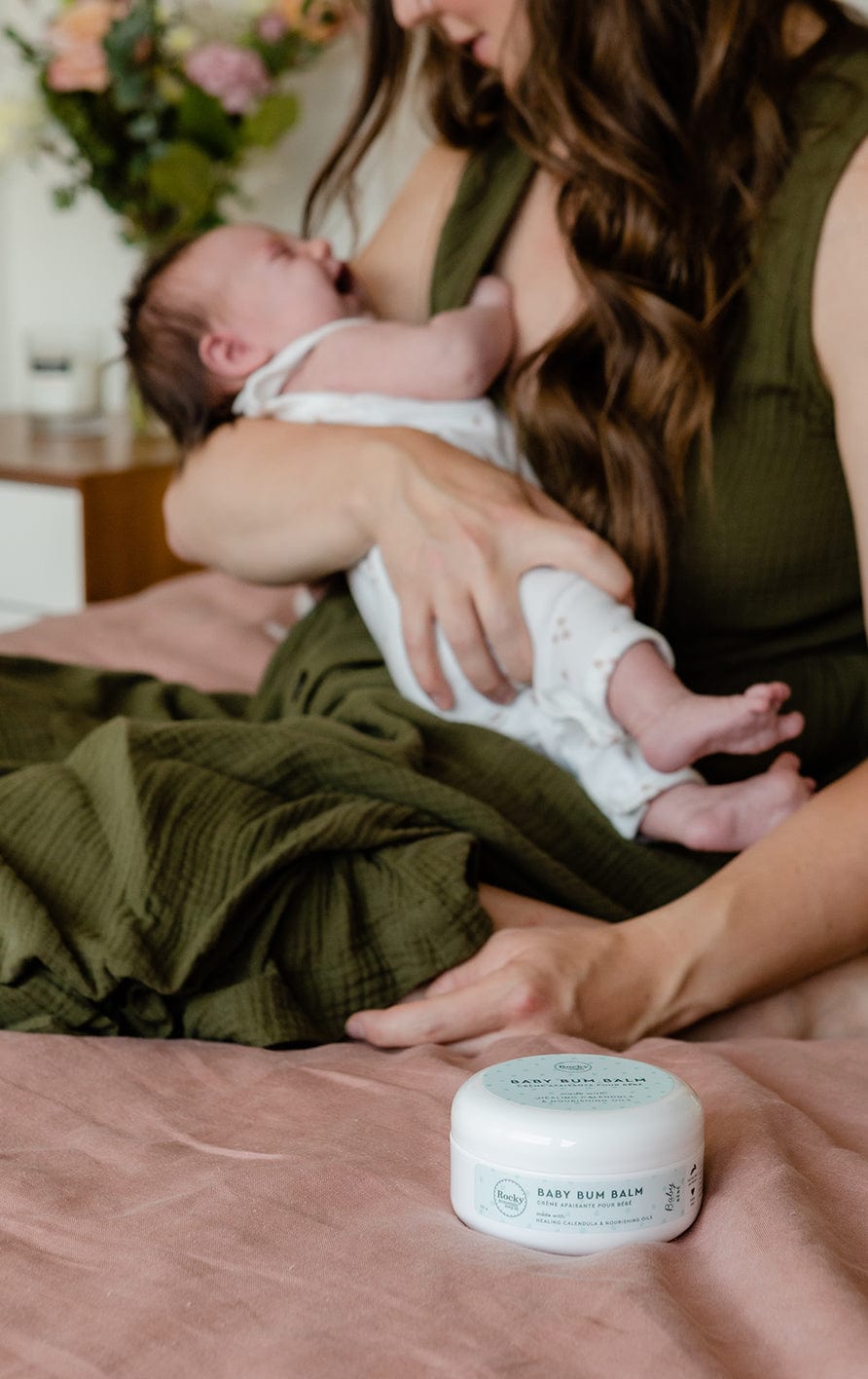 a container of baby bum balm, with a mother and child in the background